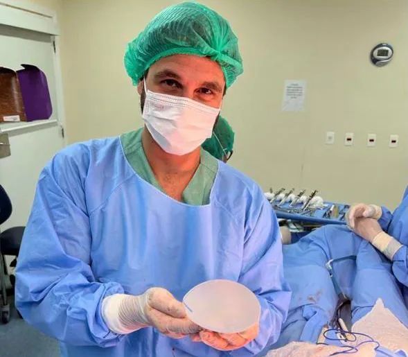 Dr. Orido Felipe segurando implante de silicone no centro cirúrgico.